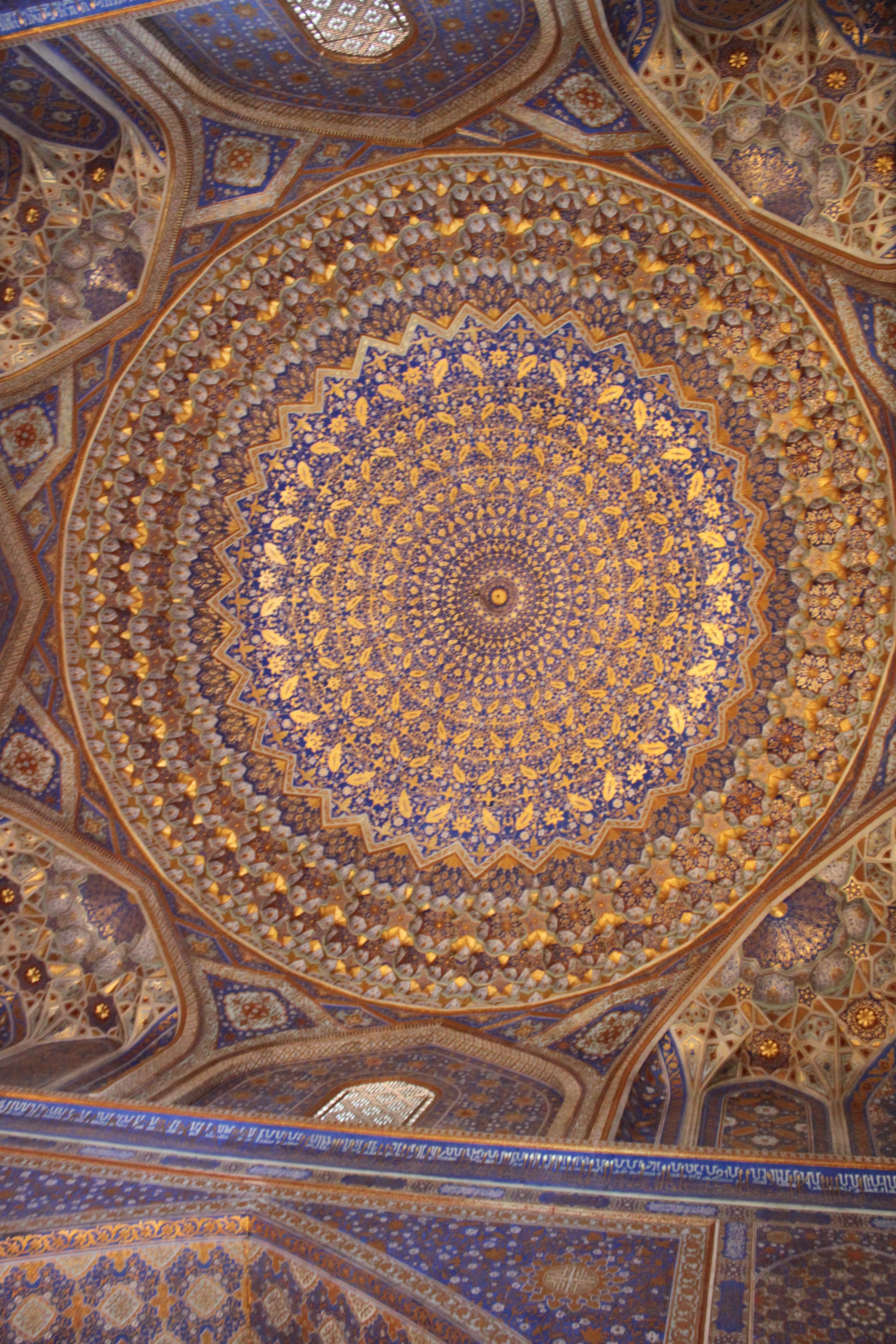Blue and gold dome inside the Tilya-Kori prayer hall, with a central rosette and radiating foliage