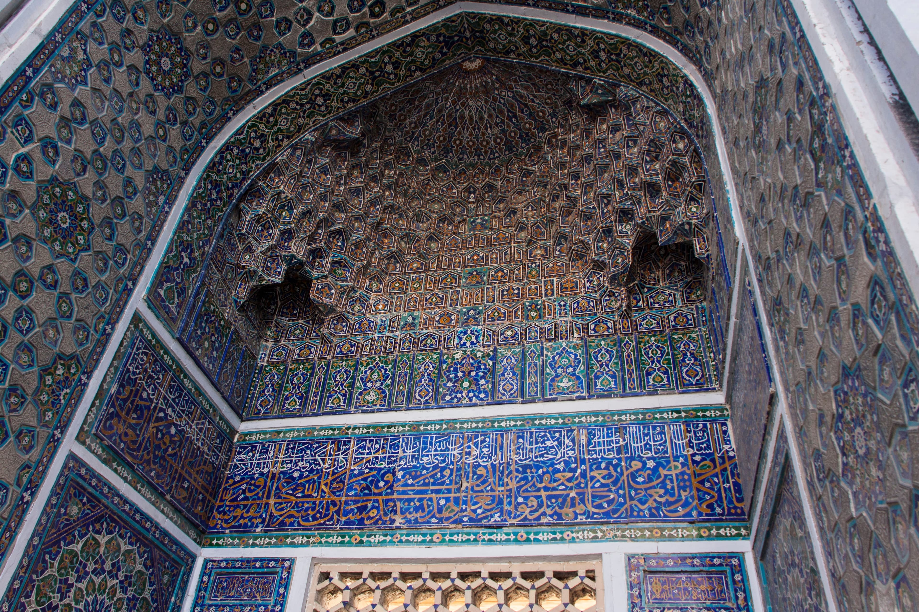 Tiered niches in the Ulugh Beg portal vault above a blue calligraphic band and patterned side walls
